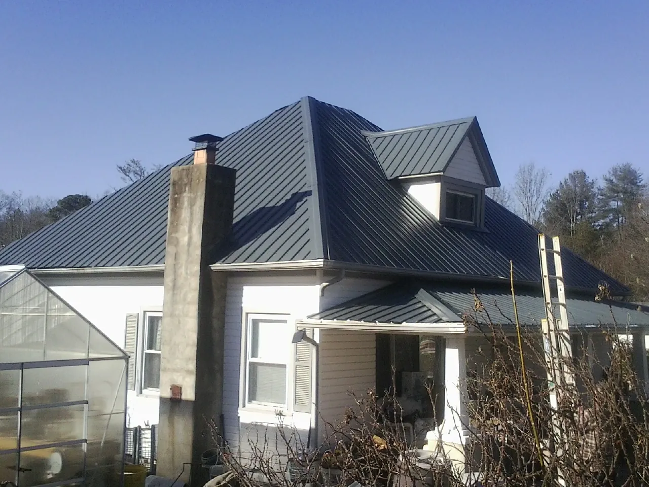 Dark blue standing seam metal roof on a white farmhouse with dormer — Slate & Tile Roof Repair by Roofing Brothers in Northford