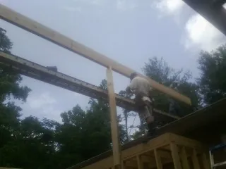Carpenter setting a ridge beam over a new addition frame — Ice Dam Removal by Roofing Brothers in Northford