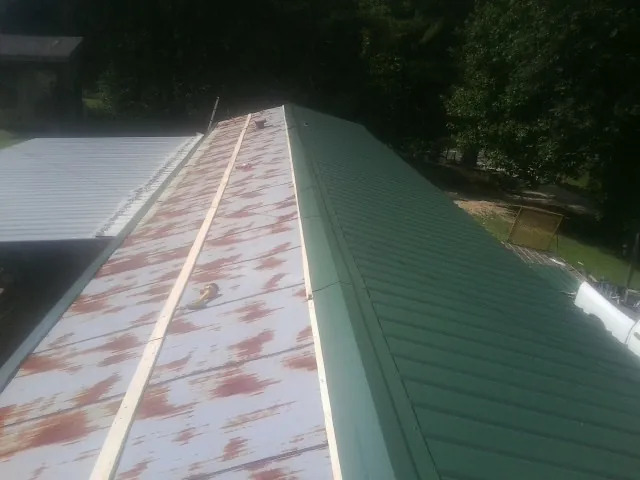 Old rusted panels beside newly installed green metal roofing — Wind Damage Roof Repair by Roofing Brothers in Northford