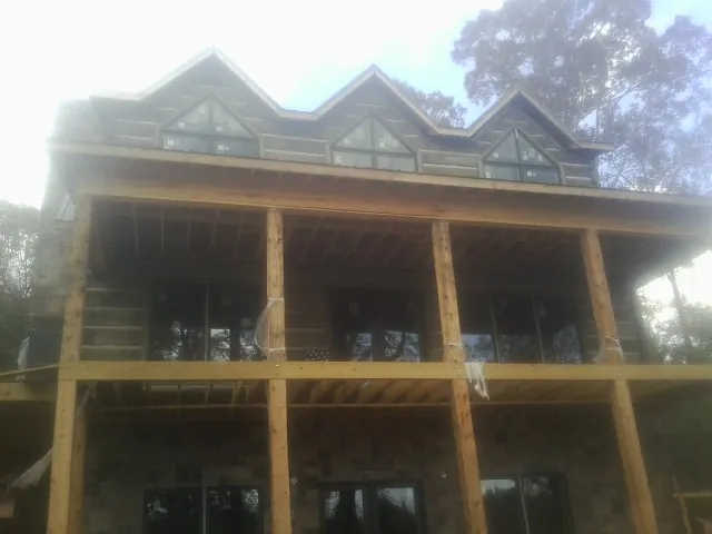 Dormers and porch framing on a large log home under construction — Roof Coating work by our crew in Northford