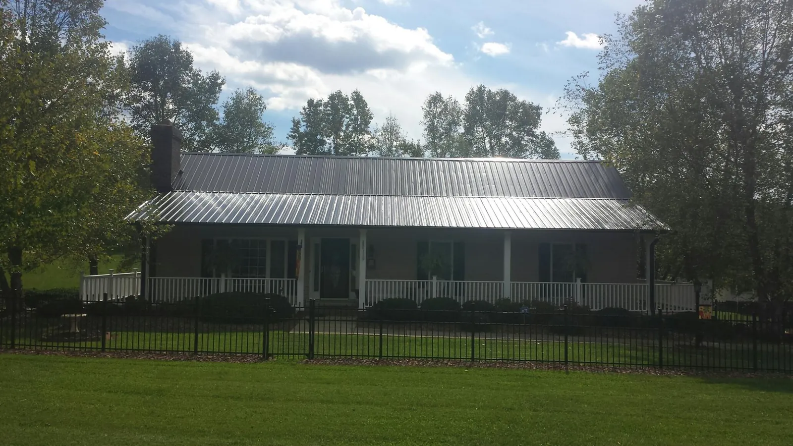 Gray metal roof on a brick ranch with a full width front porch — Gutter Guard Installation work by our crew in Northford