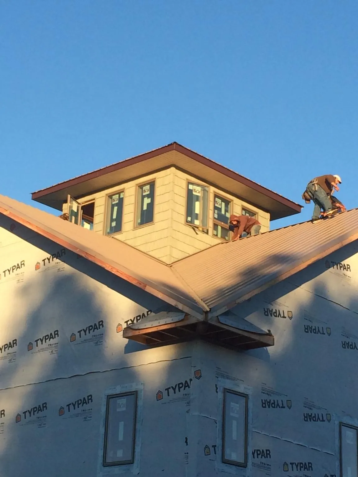 Roofers working around a rooftop cupola on a new metal roof at sunset — Roof Waterproofing in Northford by Roofing Brothers